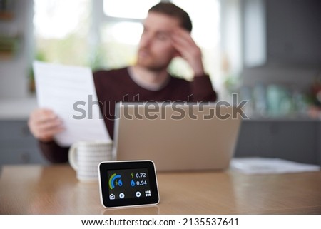 Smart Energy Meter In Kitchen Measuring Electricity And Gas Use With Man Looking At Bills Royalty-Free Stock Photo #2135537641