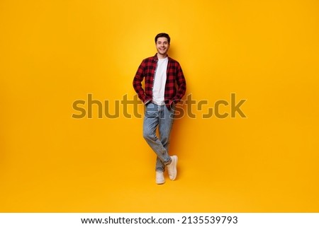 Confident Person. Portrait of cheerful casual man posing standing isolated over yellow studio background leaning on wall holding hands in pockets, smiling looking at camera, full body length banner Royalty-Free Stock Photo #2135539793