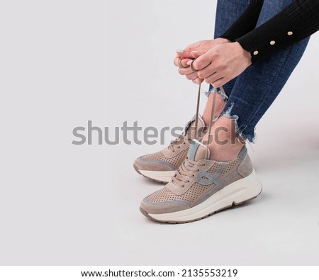 
Women's legs in stylish sports shoes on a white background