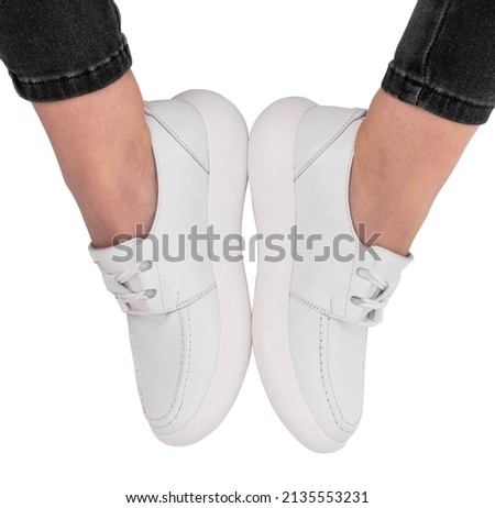 
Women's legs in stylish sports shoes on a white background