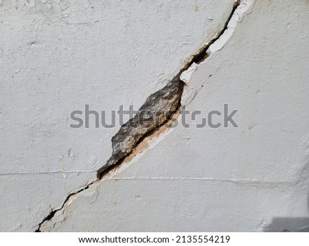 A large crack running through a cement wall. Royalty-Free Stock Photo #2135554219