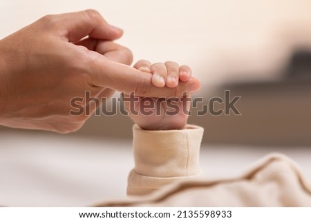 Kid is holding mom's finger that make him feel safe and secure. Strong relationship in family make children feel loved and confidence. The root for raised a good person is started from parenthood. Royalty-Free Stock Photo #2135598933