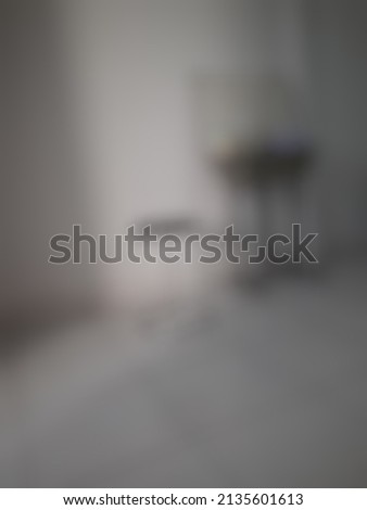Defocused abstract background of a white-floor room completed with a round chair, iron table, and a whiteboard
