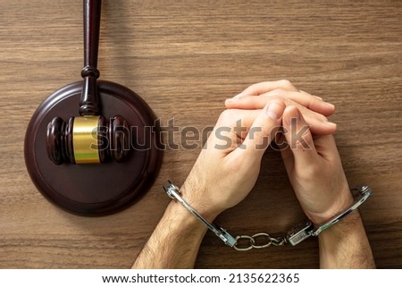 Handcuffed Convict, Law offender and Justice. Court sentence Prison. Handcuff locked and judge gavel on a wooden table, top view. 

 Royalty-Free Stock Photo #2135622365