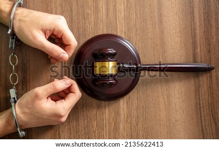 Handcuffed Convict, Law offender and Justice. Court sentence Prison. Handcuff locked and judge gavel on a wooden table, top view. 

 Royalty-Free Stock Photo #2135622413