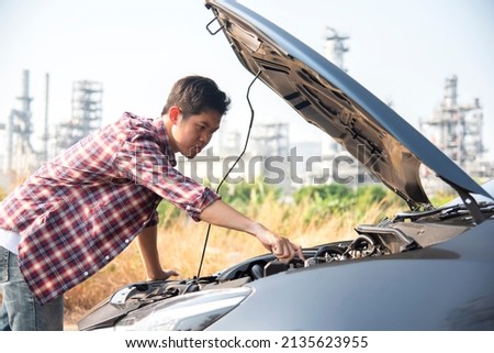 Man fixing a car problem after vehicle breakdown on the road,Traffic warning sign on road with car and driver on background