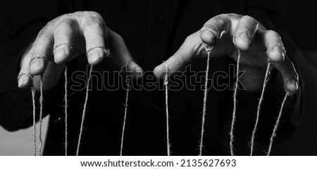 Influence and manipulation concept. Man hands with strings on fingers for control, abuse. High quality photo Royalty-Free Stock Photo #2135627693