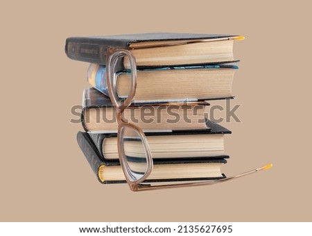 Books stack with eyeglasses on pastel background. Reading, knowledge getting, research conducting, personal development concept. High quality photo
