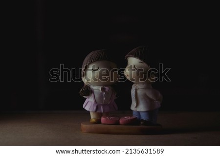 Low key photography of cute figurines of boy and girl kissing