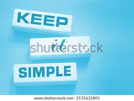 Keep it simple words on wooden blocks on dark gray background. Business copywriting concept.