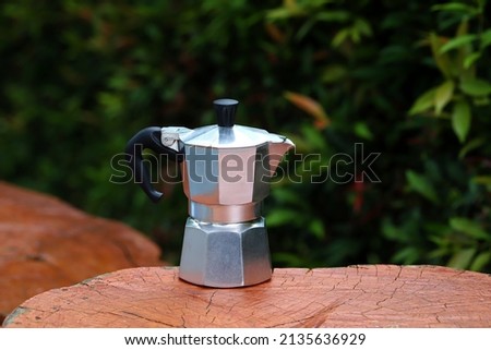 Moka pot in wooden table with green leaves background
