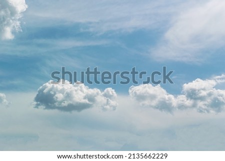 Several white clouds with a clear shape against a blue sky with cloudy haze