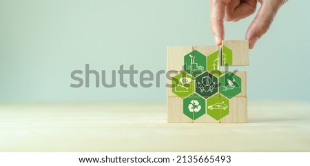 Save of earth, saving environment, net zero emissions concept. Green business and sustainable development. World earth day. Hand puts wooden cubes with clean energy icon standing on eco friendly icon. Royalty-Free Stock Photo #2135665493