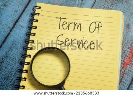 Term Of Service wording with magnifying glass and book 