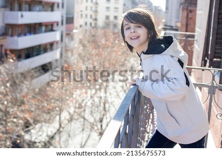 Child, standing on a balcony in a flat in Barcelona, enjoying sun and nice winter weather, Spain