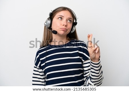 Telemarketer caucasian woman working with a headset isolated on white background with fingers crossing and wishing the best