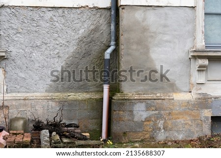 Water damage of a house. Wet exterior wall caused by a leakage in a tube of the roof gutter. Rain water is absorbed by the building. A time and cost expensive repair is necessary. Royalty-Free Stock Photo #2135688307