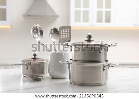 Set of stainless steel cookware and kitchen utensils on white table indoors Royalty-Free Stock Photo #2135690545