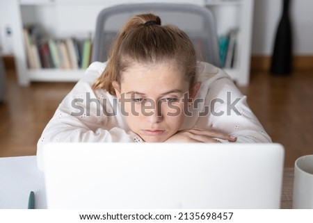 Bored female student in front of laptop paying attention to virtual class. Anxiety and depression on college students concept