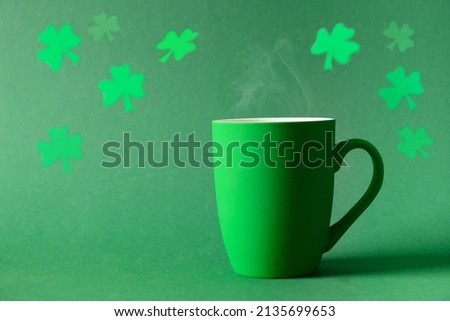 Patricks day celebration with cozy coffee in green cup or tea mug on green background. Space for text. Festive monochrome greeting card.