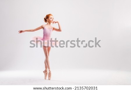 Little ballerina dancer in a pink tutu academy student posing on white background Royalty-Free Stock Photo #2135702031