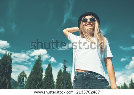 Freedom young woman carefree and happy with open arms on blue sky with hypnotizing sky in background. Caucasian girl in white shirt and jeans, feeling happiness enjoying her travel vacation