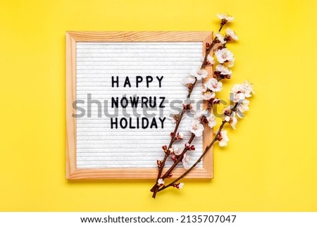 Sprigs of apricot tree with flowers on yellow background Text Happy Nowruz Holiday Concept of spring came Top view Flat lay Hello march, april, may, persian new year Greeting card