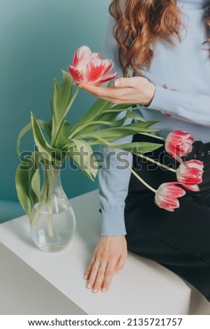 Girl in a blue sweater next to tulips