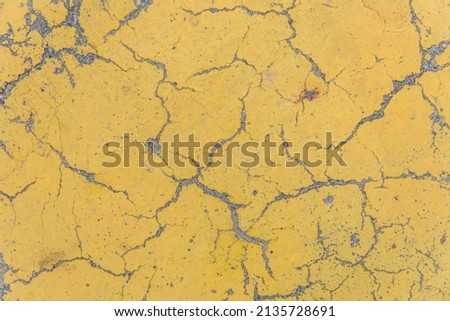Cracks on yellow paint concrete surface cracked weathered cement worn texture broken abstract damaged pattern background.