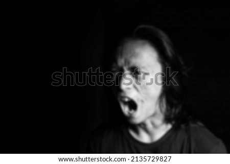 blurred on black and white head shot of a man looking for a fight. best for anger, mad, frustration, bipolar dissorder, mental health issues, mental issues background.