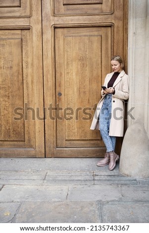 Attractive elegant woman looking at smartphone screen texting messaging online in the street