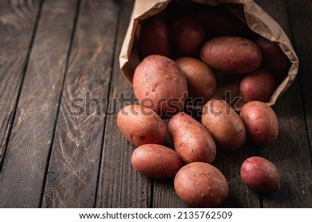 New raw red potatoes in paper bags on wooden background Royalty-Free Stock Photo #2135762509