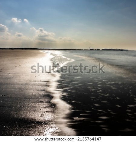 A picture of a calm north sea located in belgium.  Small aves of the ocean water.