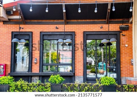 Outdoor mock up of store and shop front template - front view vintage black grey shop tone with blurred windows display,  vintage lamp green bush plant and orange brick wall.