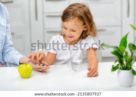 A small smiling child with pills or dragees taking medications, vitamin food supplements, health care, treatment concept. Full multivitamin formula with minerals. Royalty-Free Stock Photo #2135807927