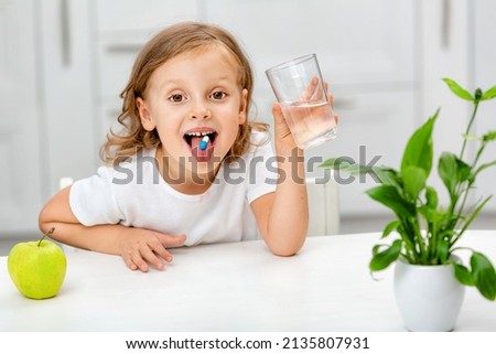 child with a pill dragee on her tongue. Taking medicine, vitamin supplements, health care, treatment concept. Full multivitamin formula with minerals Royalty-Free Stock Photo #2135807931