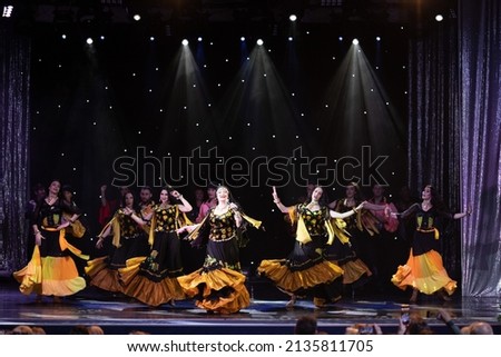 A group of musicians, singers and dancers in gypsy costumes perform on stage.