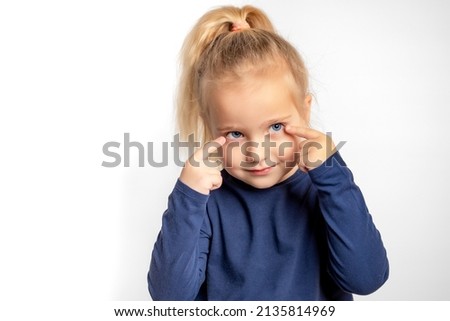 A cute little girl touches her eyes with her fingers. The concept of vision correction in children. The child experiences vision problems and complains to parents. Prevention of astigmatism.