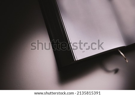 One open thick book on white table in the dark. 
