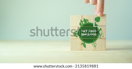 Net zero emissions concept. Carbon neutral. Climate neutral long term strategy. Sustainable business development. Green business. Hand put wooden cubes with net zero emissions icon on grey background. Royalty-Free Stock Photo #2135819881
