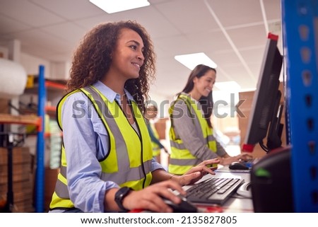 Female Staff In Busy Modern Warehouse Working On Computer Terminals Royalty-Free Stock Photo #2135827805