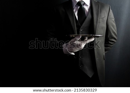 Portrait of Butler or Waiter in Dark Formal Suit and White Gloves Elegantly Holding Silver Serving Tray. Copy Space for Service Industry and Elite Hospitality. Royalty-Free Stock Photo #2135830329