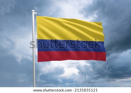 Colombian flag on a flagpole waving in the wind on a dramatic cloudy sky background. Flag of Colombia