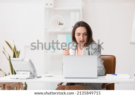 Young secretary drinking coffee while working in office