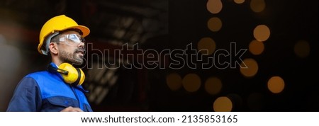 Engineer or young male worker wearing a helmet wearing glasses In an industrial plant, stack bokeh. Banner cover. Royalty-Free Stock Photo #2135853165