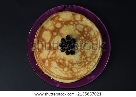 Delicious fried pancakes with frozen currants isolated on a black background. A great treat for Shrovetide