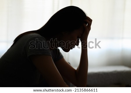 Silhouette photo of young Asian woman feeling upset, sad, unhappy or disappoint crying lonely in her room. Young people mental health care problem lifestyle concept. Royalty-Free Stock Photo #2135866611