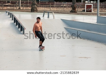 Man riding skateboard in urban street skatepark. Casual guy wearing shorts and bare chest. Leisure activity, sport extreme, city lifestyle concept