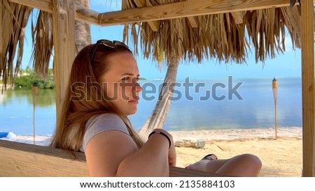 Paradise beach - Young woman sitting on a bench enjoying the Caribbean atmosphere - travel photography