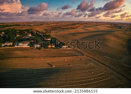 Aerial drone photography of landscape with houses and plowed agricultural field and already harvested wheat grains. Horizontal photo and selective focus. 